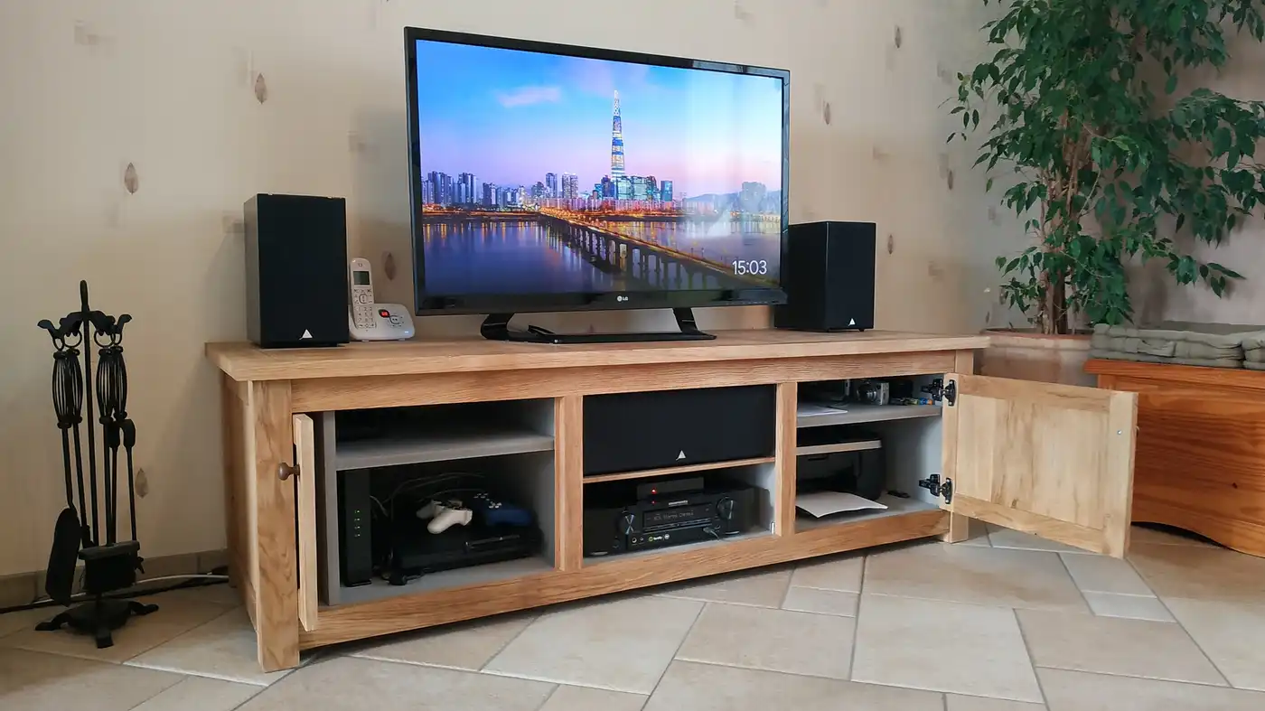 Meuble TV. Menuiserie en chêne massif, intérieur en MDF teinté masse de couleur gris clair. 2 portes dont 1 porte pouvant s'effacer dans son logement.